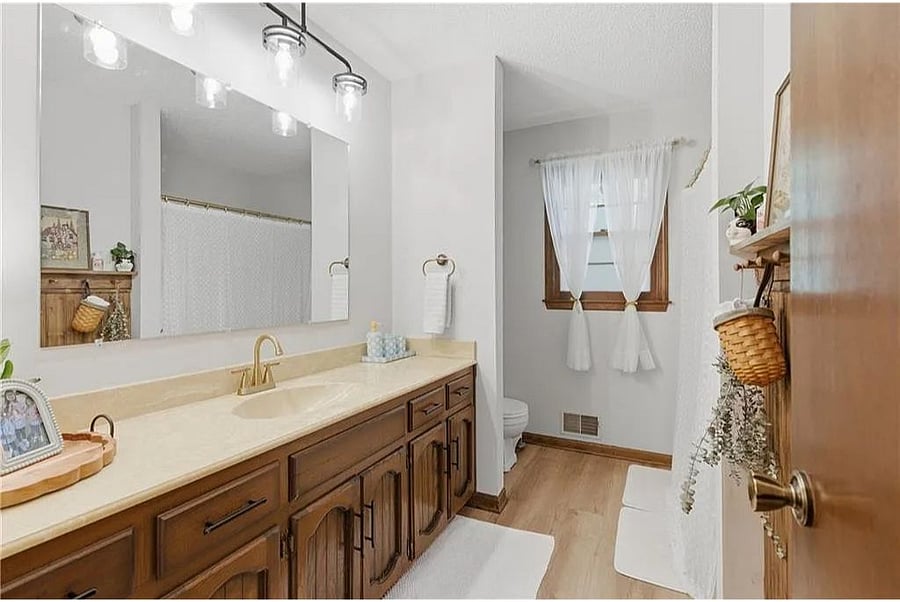 Bright and spacious bathroom with warm wood cabinetry, modern lighting, and a clean inviting layout.