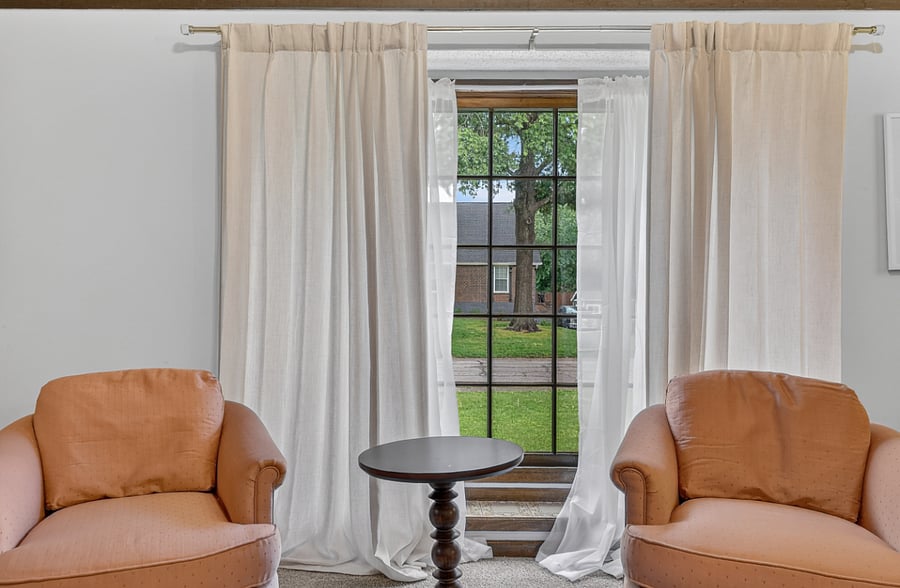 Bright sitting area with floor to ceiling windows, soft natural light, and peaceful outdoor views.