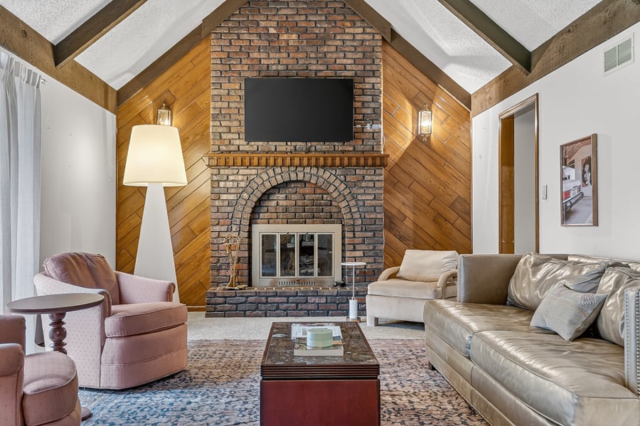 Warm and inviting living room with soaring ceilings, cozy seating, and a stunning brick fireplace centerpiece.