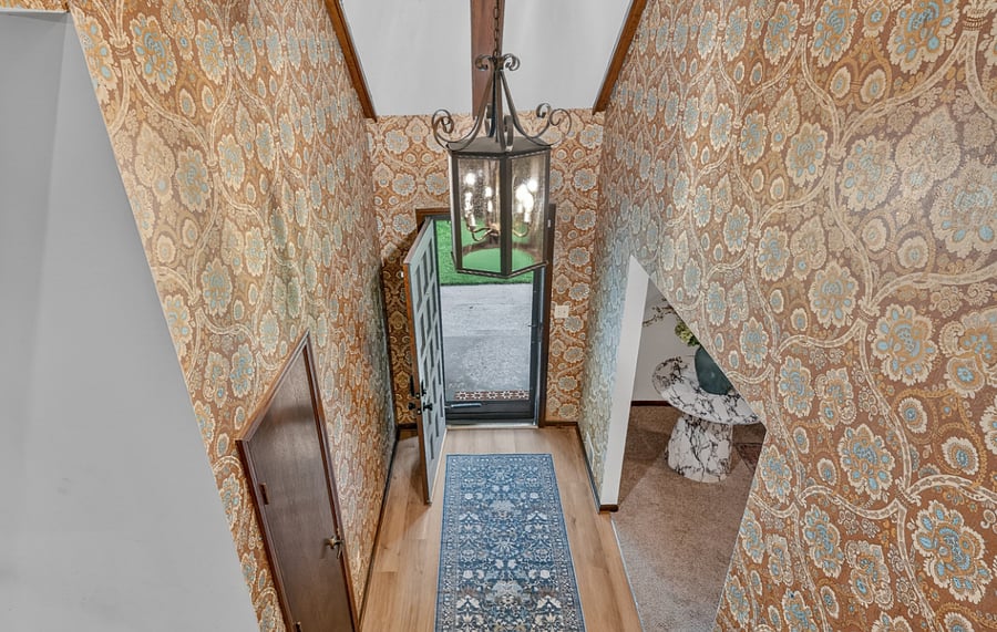 Unique lower staircase entry with patterned wallpaper and charming architectural character.