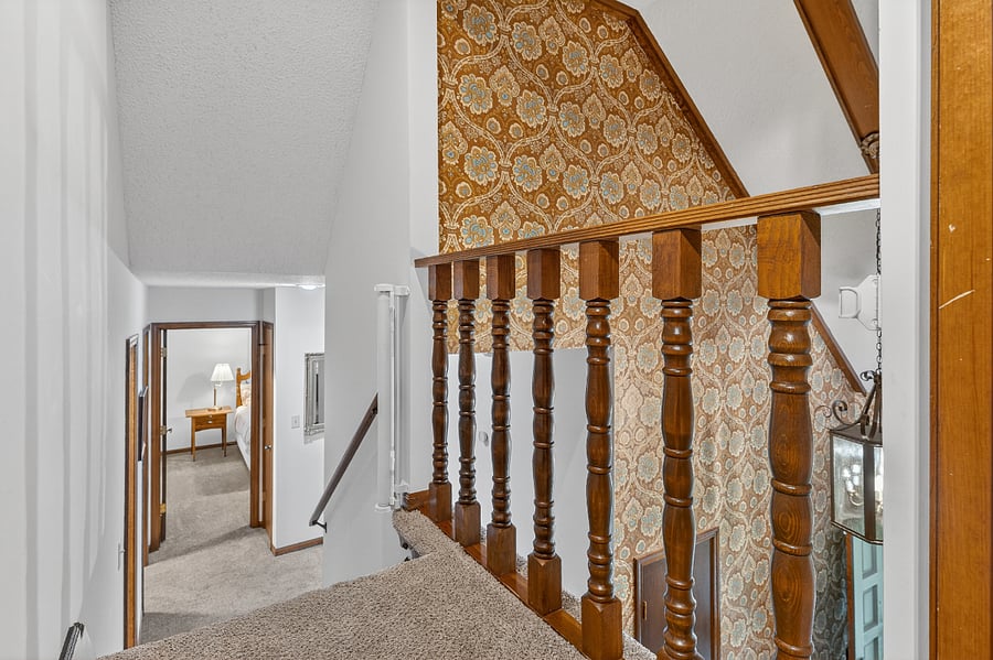Staircase landing with warm wood railings and elegant vintage inspired design elements.