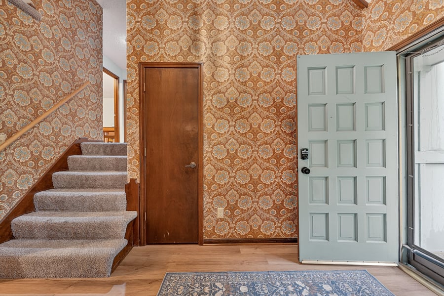Vintage inspired entry area featuring bold wallpaper, warm wood accents, and timeless character.