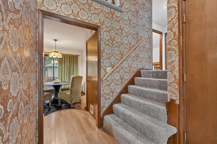 Elegant staircase with classic wallpaper details and a welcoming open concept foyer design.
