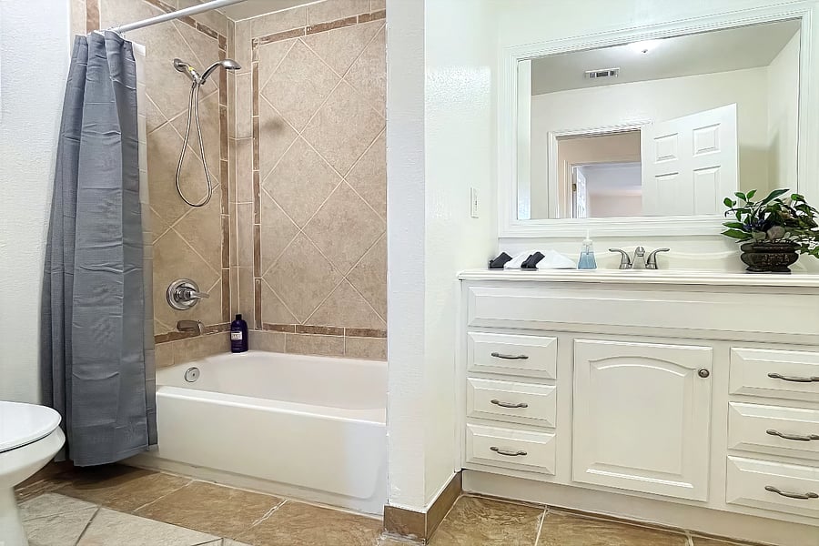Large bathroom with tub, toilet and single vanity sink.