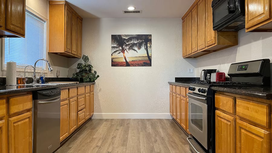 Kitchen with refrigerator, gas stove, oven, dishwasher, microwave, toaster, coffee maker, hot water kettle, and reverse osmosis purified drinking water system.