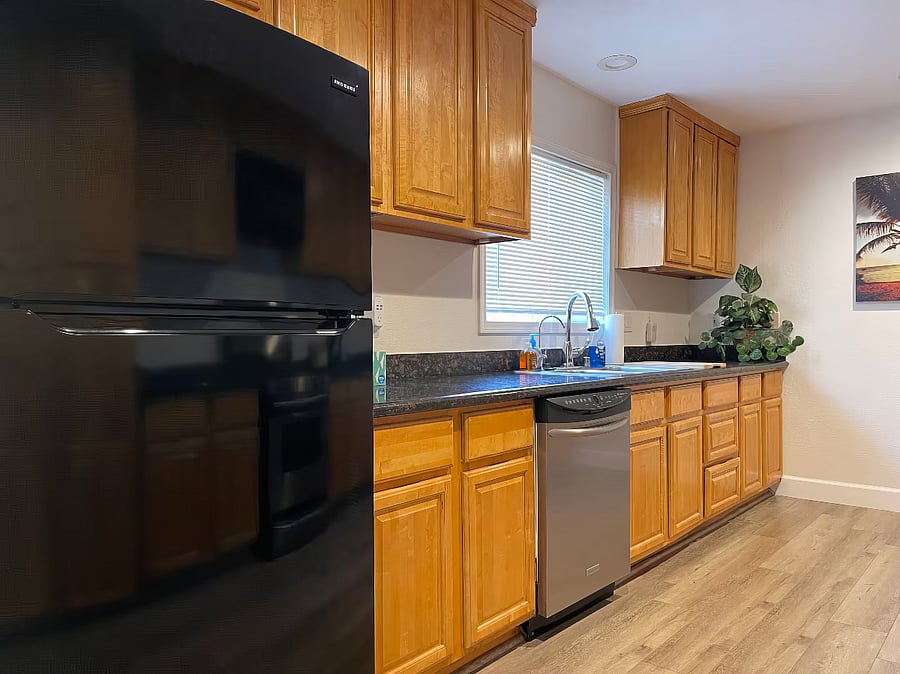 Kitchen with refrigerator, gas stove, oven, dishwasher, microwave, toaster, coffee maker, hot water kettle, and reverse osmosis purified drinking water system.