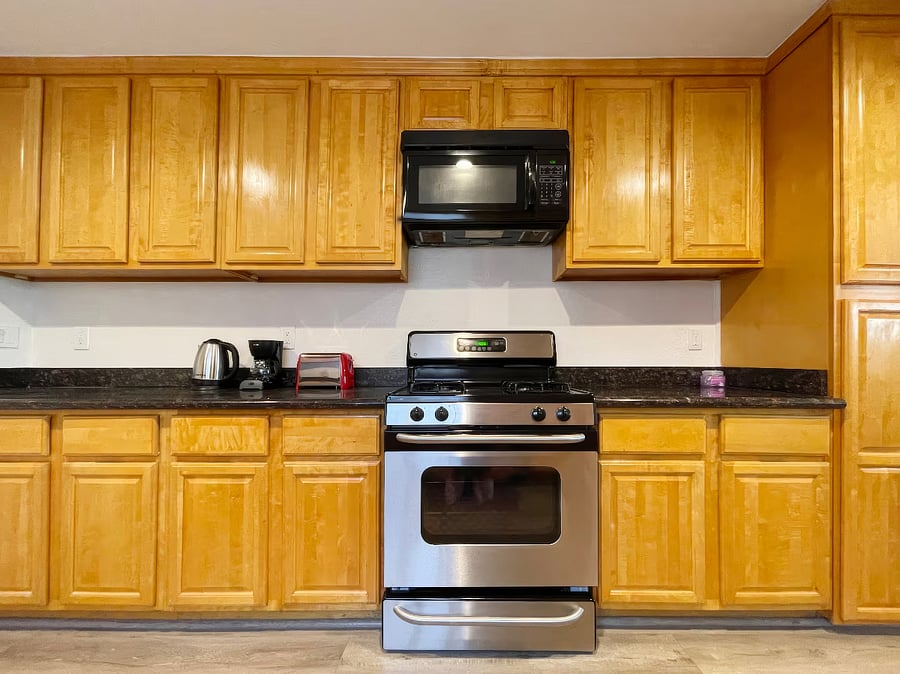 Kitchen with refrigerator, gas stove, oven, dishwasher, microwave, toaster, coffee maker, hot water kettle, and reverse osmosis purified drinking water system.