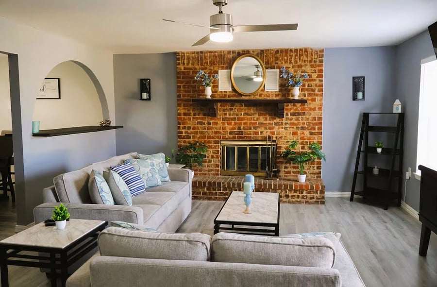 This bright living room features an exposed brick fireplace as the focal point and soft lighting. Sink into the plush, modern sofasperfect for movie nights, conversation, or unwinding after a day out.