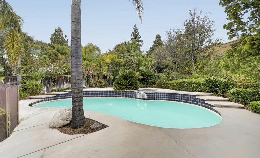 The backyard features a private pool surrounded by mature trees and beautiful landscaping.