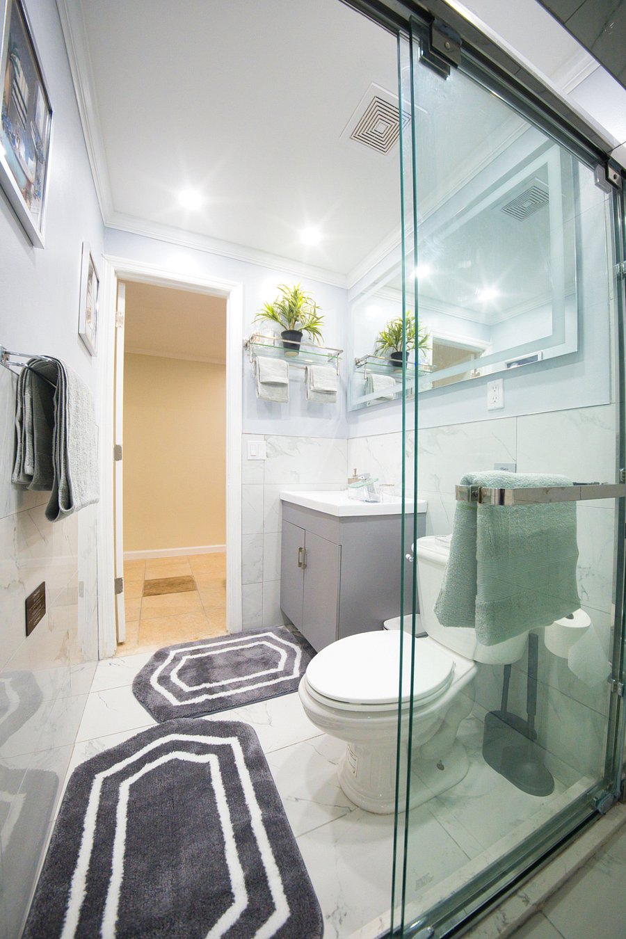 This full bathroom offers a bright, refreshing atmosphere with matching towels, a high-quality sliding glass shower door, and a custom sink. A clean, modern space designed to help you unwind.