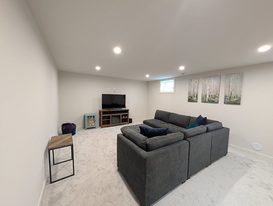 Living room with large sectional, board games, and TV (finished basement)