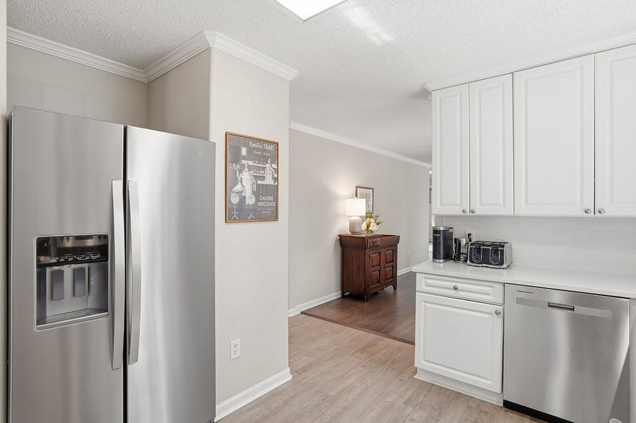 View from Kitchen with full refrigerator with filtered water and ice maker in foreground, leading to Dining area with old fashioned dry sink stocked full of barware where you can make all your favorite drinks to enjoy inside or outside on the screened in porch..