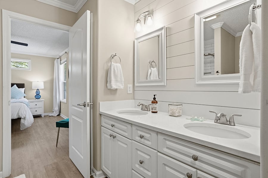 Master bathroom with double sinks, tiled shower, and linen closet stocks with towels.