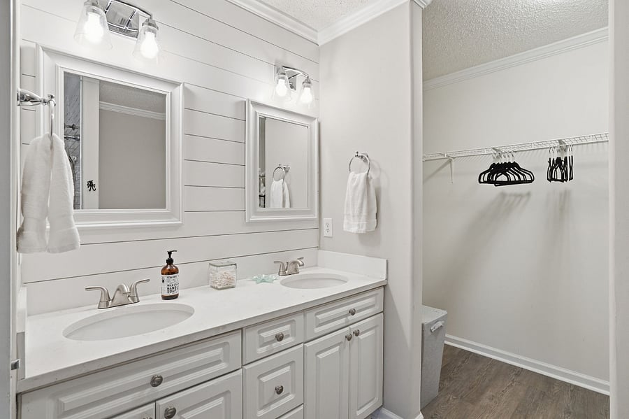 Master bathroom with view to walk in closet with laundry basket, and extra sheets, pillows and blankets.