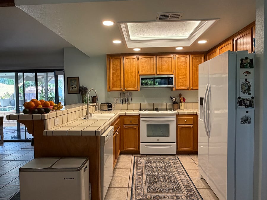 Kitchen with full-size fridge, electric stove/oven, and instant hot water faucet.