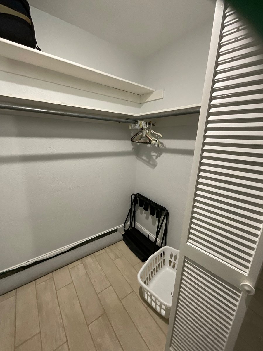 Walking closet with beach cart and umbrella and beach chair.