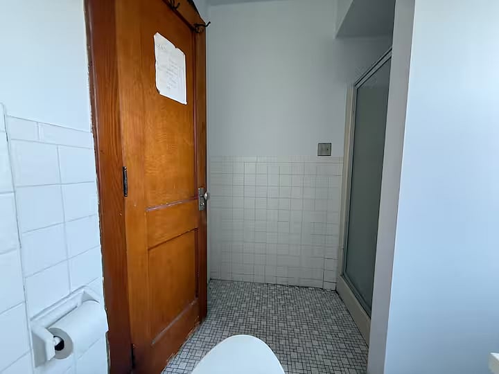 Second floor shared bathroom, shower, toilet, and vanity sink. View from toilet.