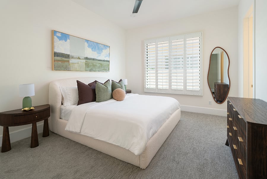 King bedroom with upholstered headboard, nightstands and dresser, plantation shutters, ceiling fan, and a dedicated walk-in closet.