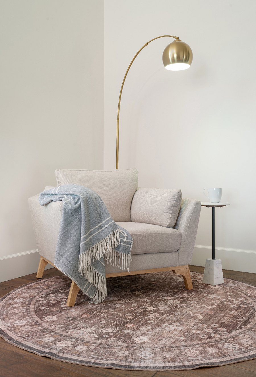 The primary suite is an oversized retreat spanning a king bed with Persian rug and seating area, a dedicated reading nook with oversized armchair and brass arc floor lamp, and a private workspace with full desk, sofa, and direct slider access to the patio with mountain views. Plantation shutters, ceiling fan, and a chandelier in the workspace alcove complete the suite.
