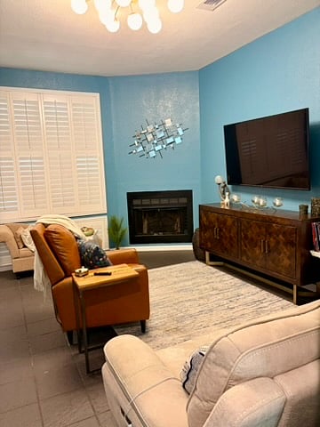 Another view of the living room featuring the inoperable wood fireplace, buffet, and a 65" inch television mounted to the wall.