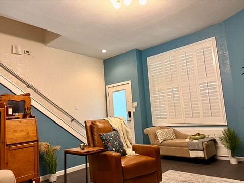 The living room with slate tile and a reclining chair, a chase lounge with storage underneath its seat, and a beautiful wood cabinet.