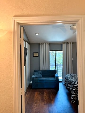 The primary bedroom with a private balcony right off of it. The blue chair contains a pullout bed allowing for one person.