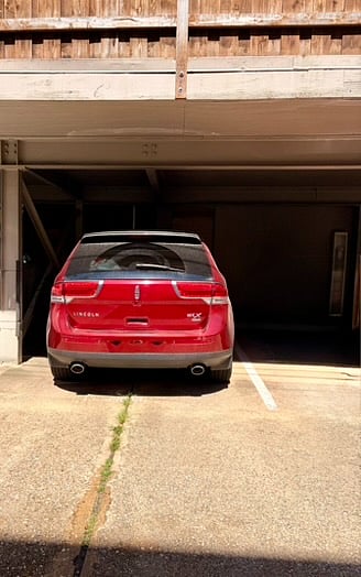 The unit features one covered, assigned, and off-street parking spot, as seen in this photo, and additional uncovered and off-street parking in the front of the building for guests.