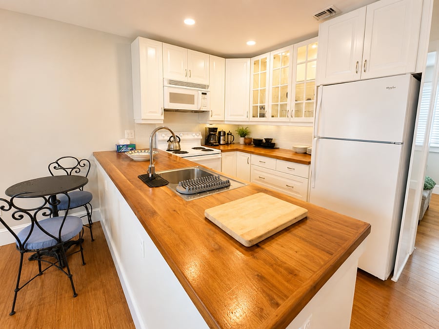 Fully equipped kitchen with glass window cabinetry and wood countertop.