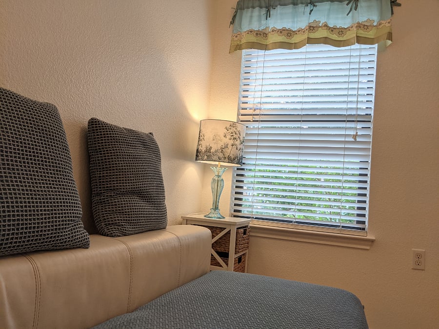 Comfy couch, table lamp and side table with a large window looking out to the front yard. What a wonderful place to read your book or just relax.