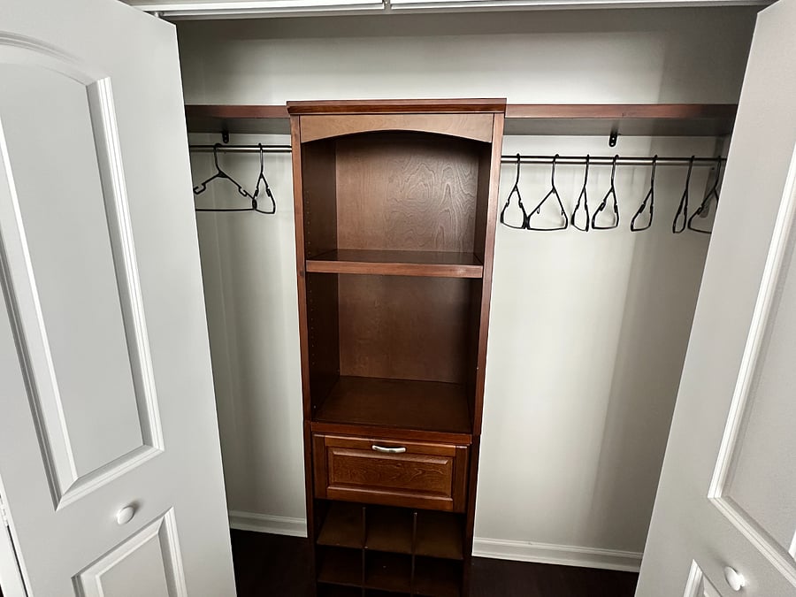 Spacious closet in main bedroom with built in wood storage structure.