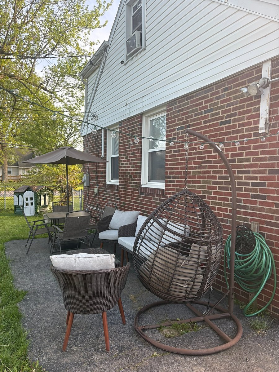 outdoor seating area in fully fenced backyard; firepit hanging inside garage with firewood