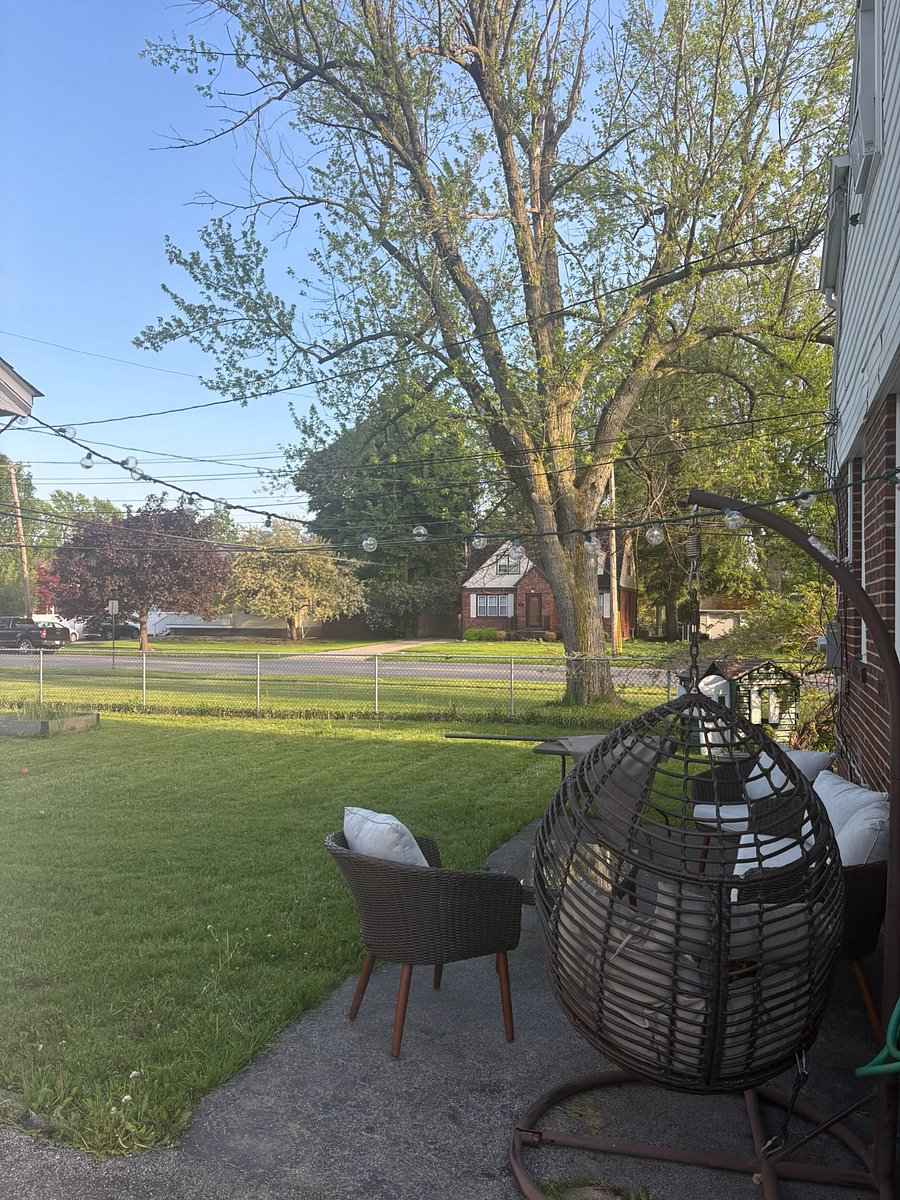 outdoor seating area in fully fenced backyard; firepit hanging inside garage with firewood