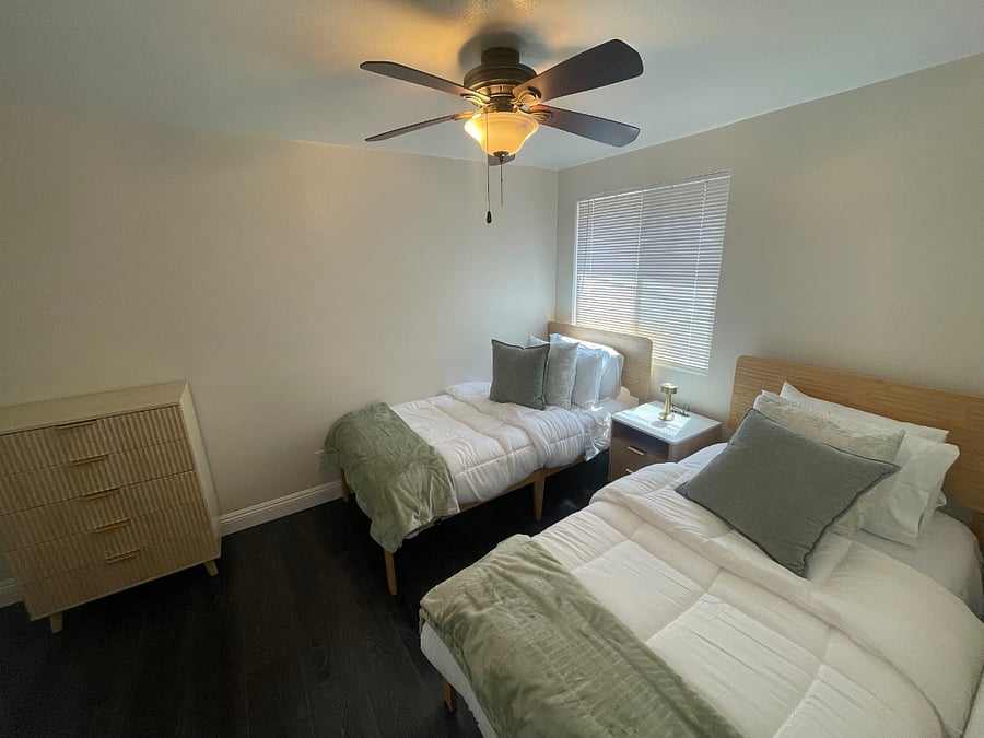 Comfortable and fully furnished bedrooms designed for restful extended stays. The primary bedroom features a queen-size bed with clean hotel-style bedding, while the second bedroom offers two twin beds ideal for friends, coworkers, or family stays. Both rooms include ceiling fans, natural light, and a clean modern feel for a relaxing stay in Los Angeles.