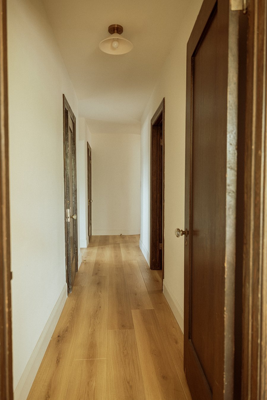 This hallway leads you through the home, with a convenient half bathroom on the left and the primary bedroom on the right. Continue down the hall to find the guest bedroom and a full bathroom.