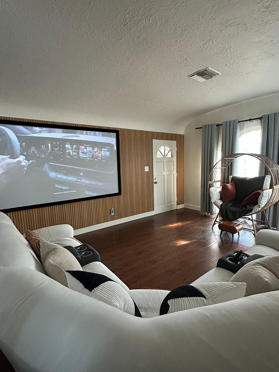 Home theater living room with oversized projection screen, reclining seating, and cupholders.
