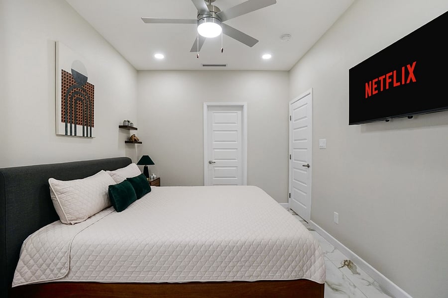 master bedroom with a king size bed, black curtains, and 43 inch smart tv
