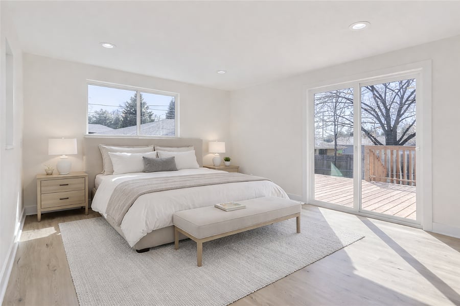 Primary bedroom with a sliding glass door opening to the private back deck. Photo is virtually staged from the prior for-sale listing. The room now features a comfortable king-sized bed, nightstands, and updated furnishings. New photos coming soon.