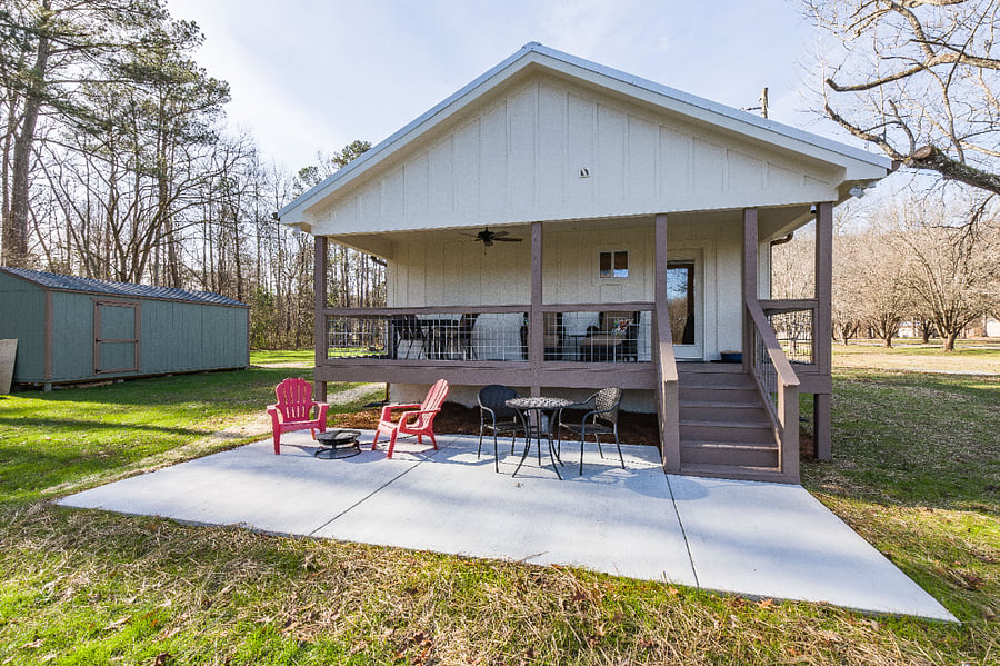 Concrete patio holds a bbq grill, plus Adirondack-style chairs and firepit.