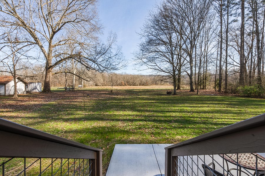 View from back porch looks at the backyard as well as an open field.