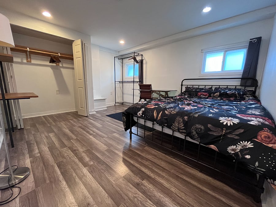 Secondary bedroom with a queen bed and a desk/workstation. It also has a closet and an additional storage/clothing rack