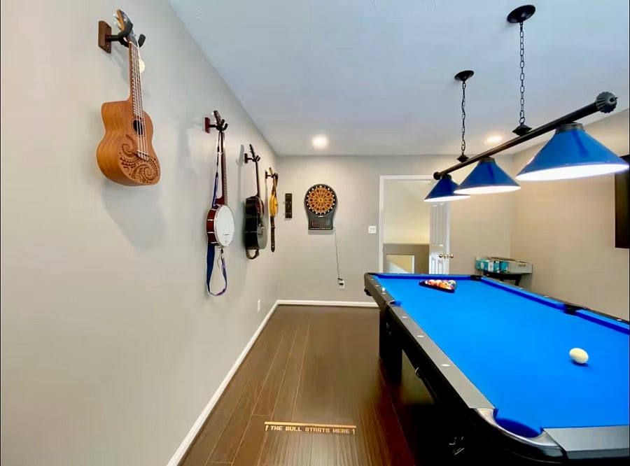 Game room with pool table, dart board, stand up arcade game console, musical instruments, and 65" Smart TV with soundbar and subwoofer.