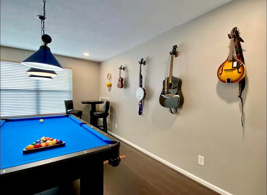 Game room with pool table, dart board, stand up arcade game console, musical instruments, and 65" Smart TV with soundbar and subwoofer.