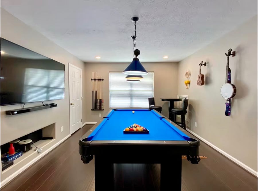 Game room with pool table, dart board, stand up arcade game console, musical instruments, and 65" Smart TV with soundbar and subwoofer.