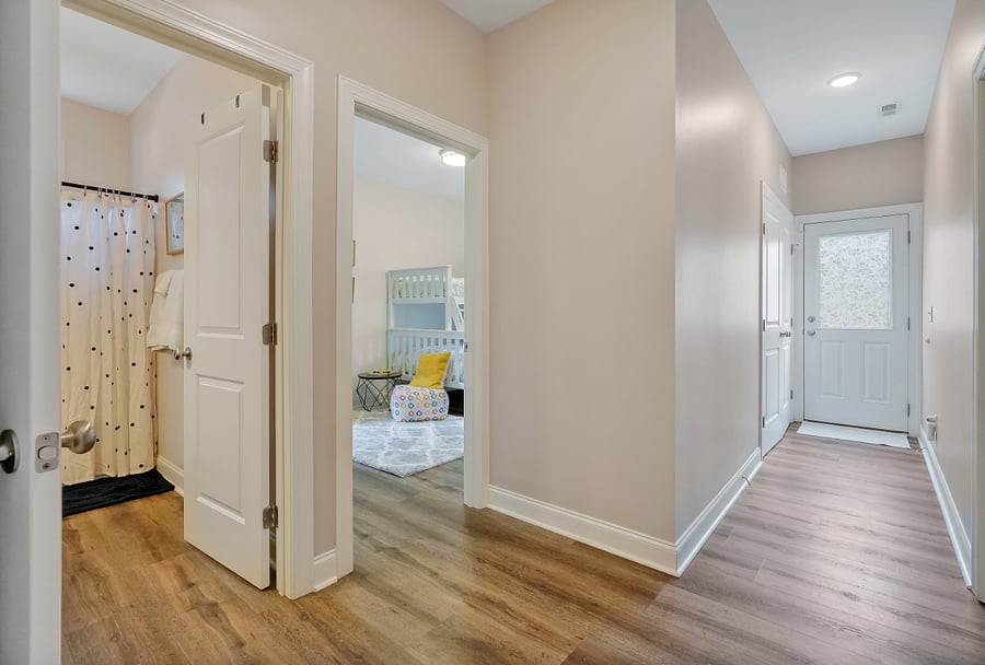 View from hallway into 2nd bedroom and full bathroom and view to washer dryer closet and door to backyard.