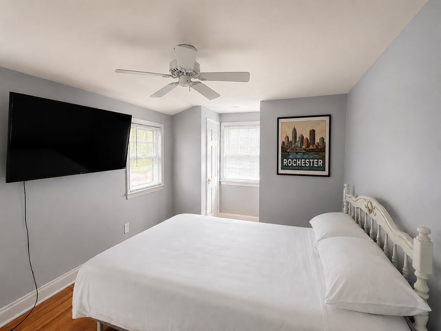 Comfortable and inviting guest bedroom featuring a full-size bed, fresh linens, hardwood floors, ceiling fan, and a wall-mounted Roku Smart TV. Whether youre staying for a few weeks or several months, this cozy space provides a relaxing retreat to unwind, stream your favorite shows, and get a great nights sleep.