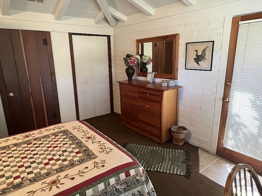 Main house second bedroom with queen bed, desk, large dresser, and closets.
