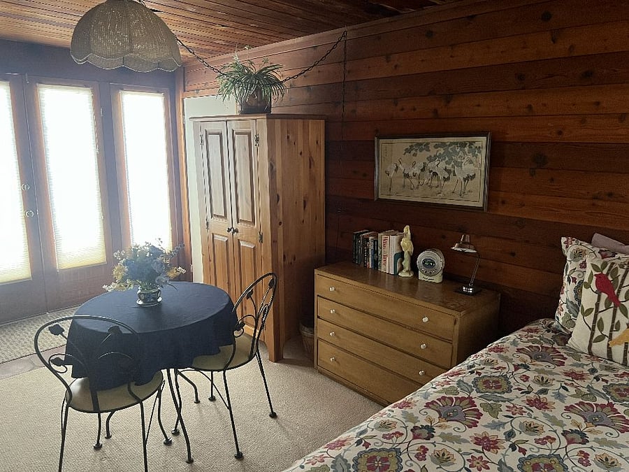 Guest house queen bedroom with small table and chairs and freestanding closet.