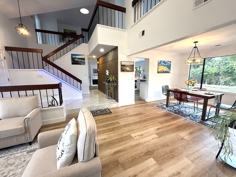 Open-concept living area with wooden floors, fireplace, and generous natural light.
