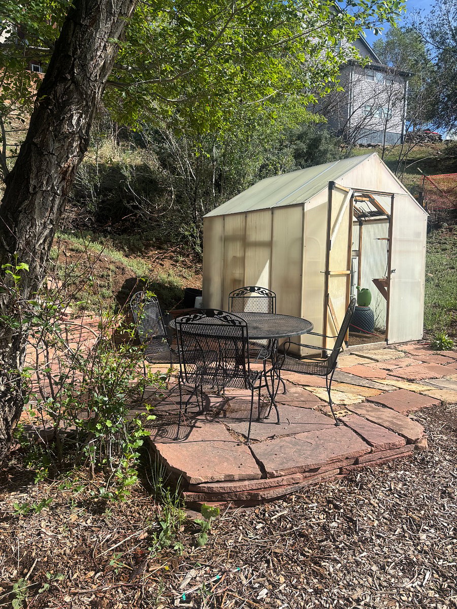 Flagstone patio on the west side of the property with table and chairs, greenhouse, and Solo Stove fire pit.