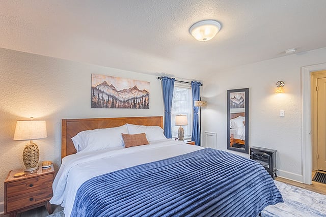 Primary Bedroom (upstairs): King bed with hybrid memory foam mattress, fireplace-style space heater, tower fan, swivel smart TV & Blu-ray, comfy chair, workspace, lots of natural light, sit-down arcade game, 2 closets, and mountain-themed decor.